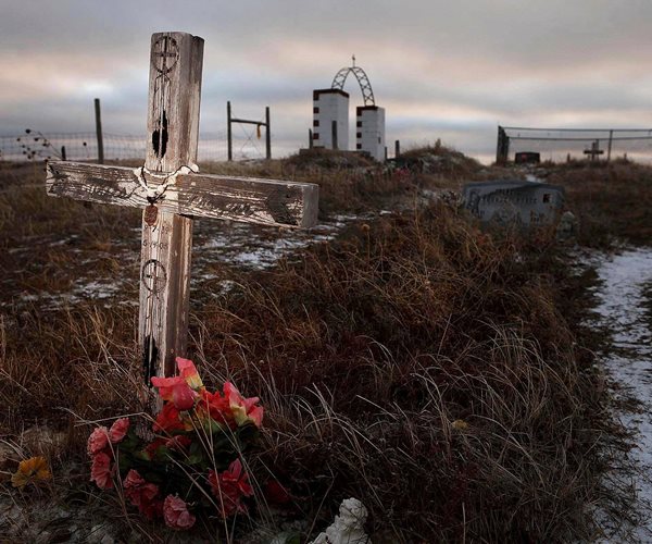 a cross and flowers lay on the dirt and snow