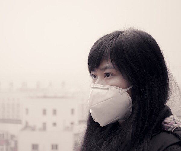 Asian girl wearing mouth mask in air pollution haze in Beijing
