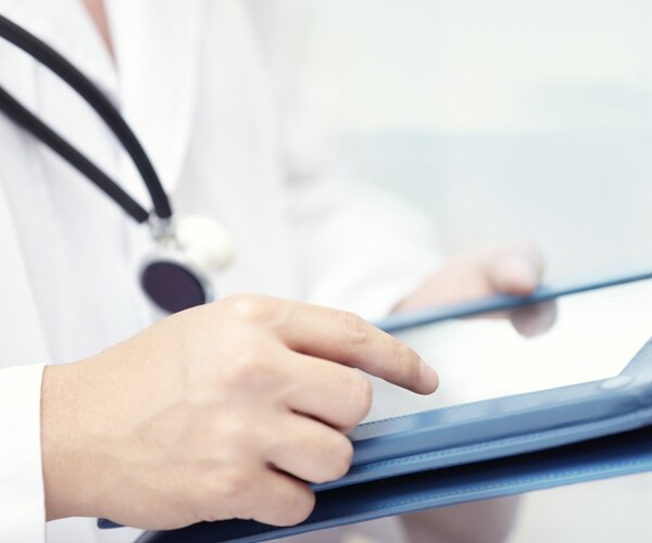 a doctor looks at test results on a tablet computer