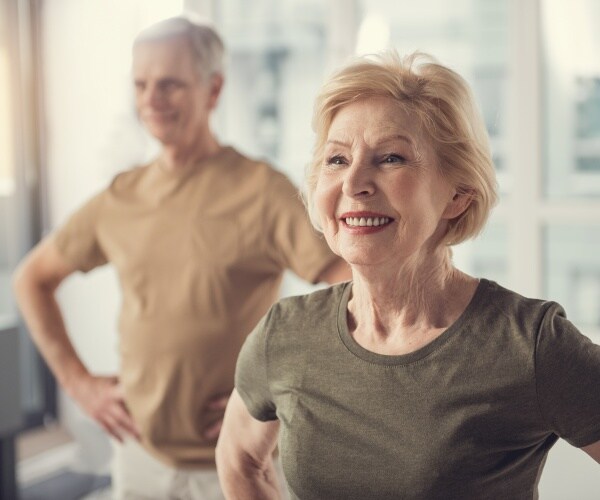 older man and woman smiling in an exercise class