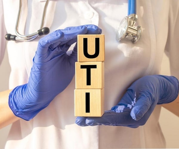 healthcare worker with blue gloves holding blocks that spell out UTI
