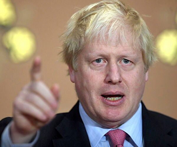 boris johnson with scruffy hair speaks and points forward with his right index finger