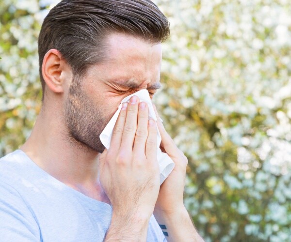 man in field sneezing