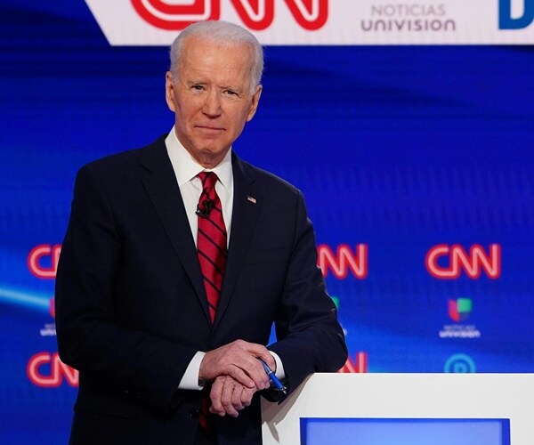 joe biden leands on a podium before a cnn debate