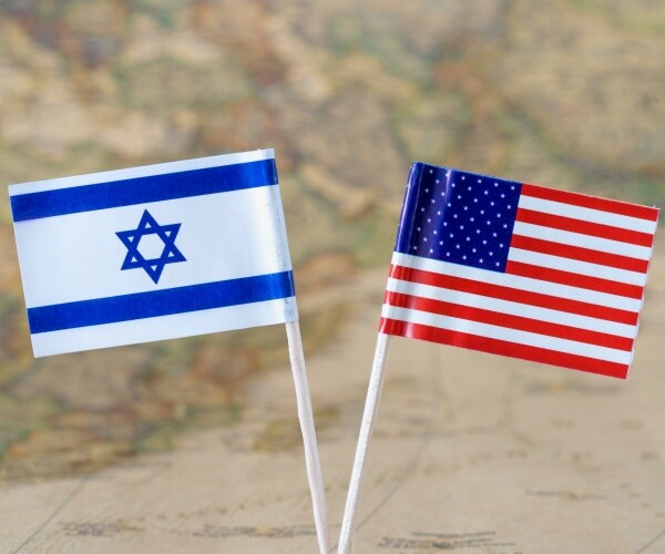 paper flag pins of israel and the us on a world map background