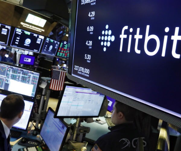 the logo for fItbit appears above a trading post on the floor of the new york stock exchange.