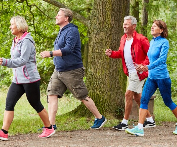 men and women walking briskly in a park together