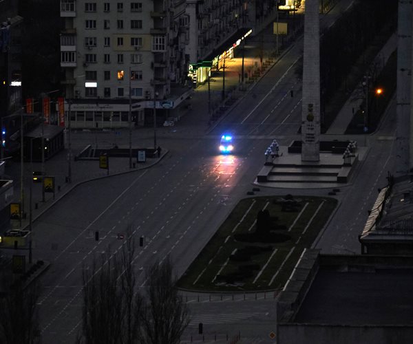 A police vehicle drives down a darkened city street.