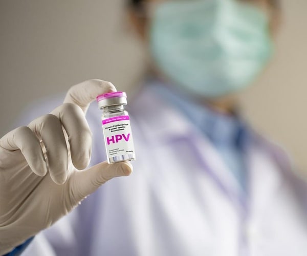 healthcare worker holding up a vial of HPV vaccine