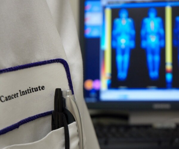 scans of patients, doctor with Cancer Institute on white coat pocket