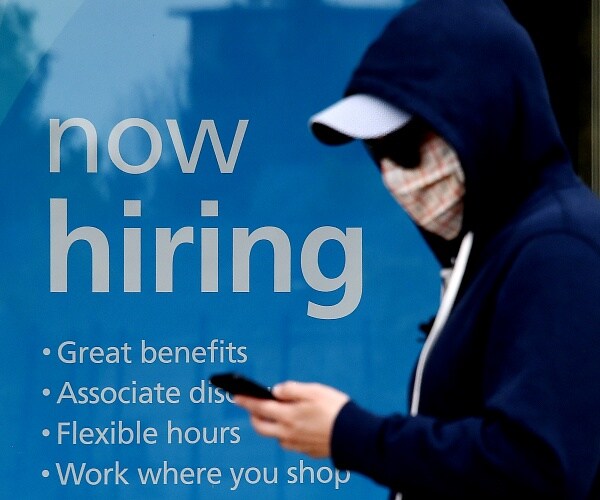 man walks past now hiring sign