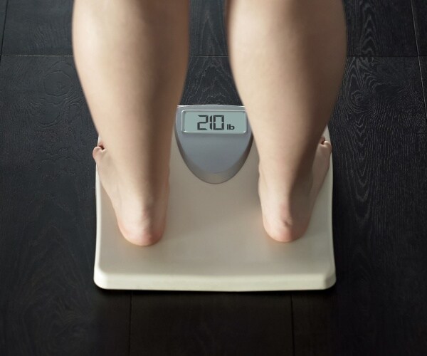 woman's legs on scale reading 210 pounds