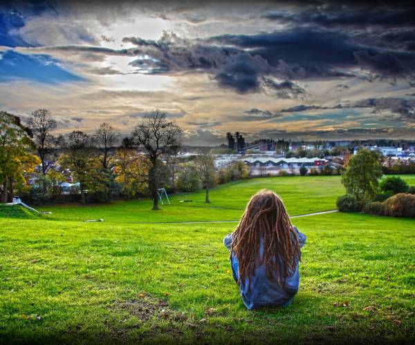 a girl sitting looking over a hillside
