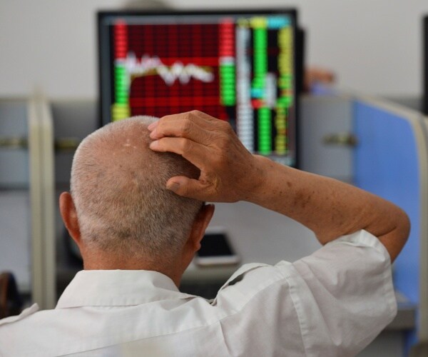 An elderly stockholder looks at the stock market data on a computer screen in a security business hall.