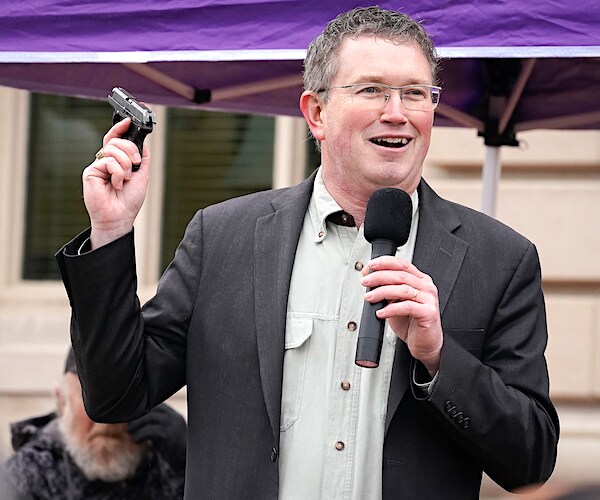 thomas massie holds up a gun while campaigning about second amendment issues