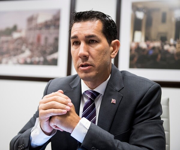 kai kahele sits with hands clasped