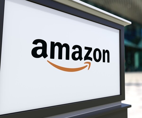 street signage board with amazon.com logo. blurred office center and walking people background

