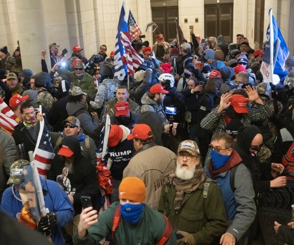 pro-trump protesters mill in the capitol in maga hats and with trump and u.s. flags