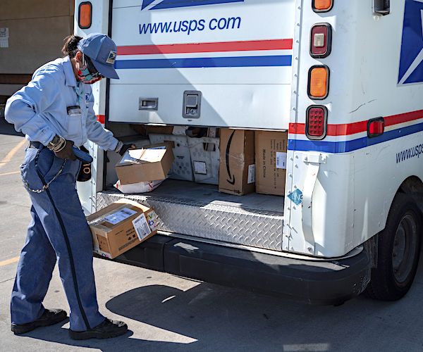 a postal worker works on packages from the back of a postal truck