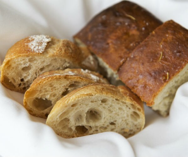 A bread basket is shown with pieces of bread lying on a white napkin