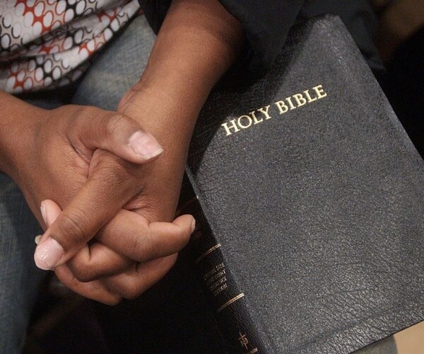  woman clutches her hands on her bible