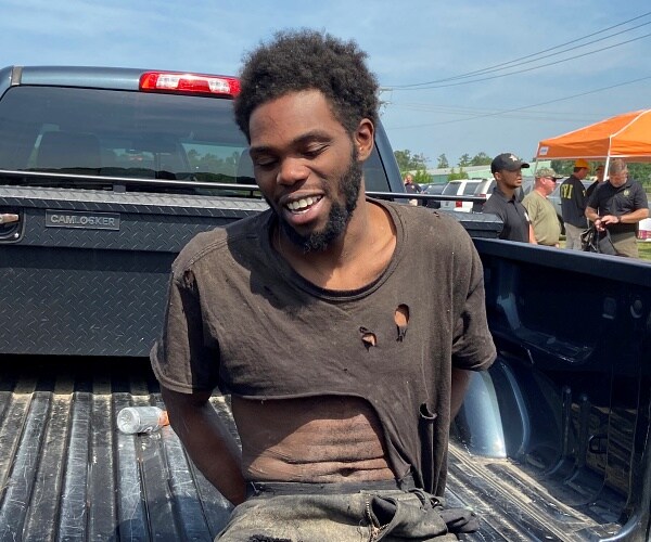 man sits on back of pickup in ripped tshirt