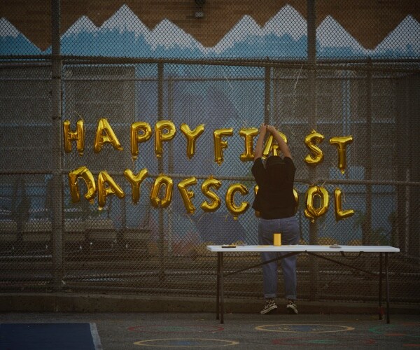 school worker decorates the school yard with happy first day of school balloon letters