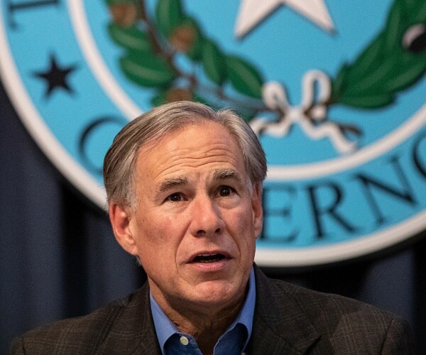 greg abbott sits behind table