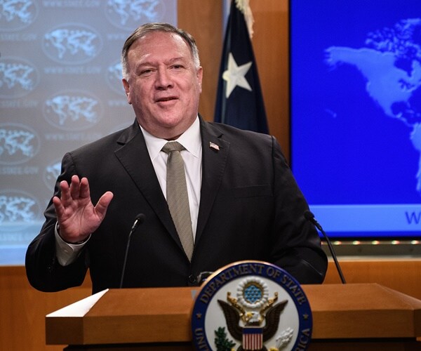 mike pompeo stands at a podium next to flags