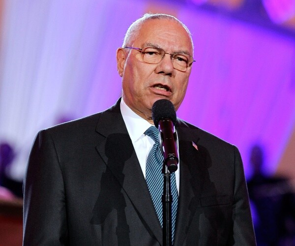 powell in a black suit and blue polka dotted tie