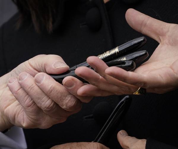 trump hands pens to someone after signing legistlation
