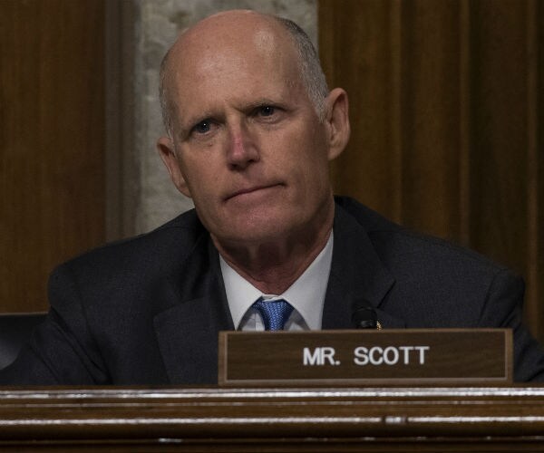 sen. rick scott is shown listening during a senate hearing
