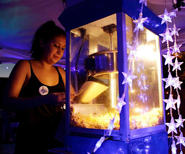 a woman scoops popcorn at a movie theatre concession stand