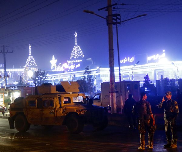 investigators framed by glowing lights of the city skyline at site of suicide bombing in kabul afghanistan