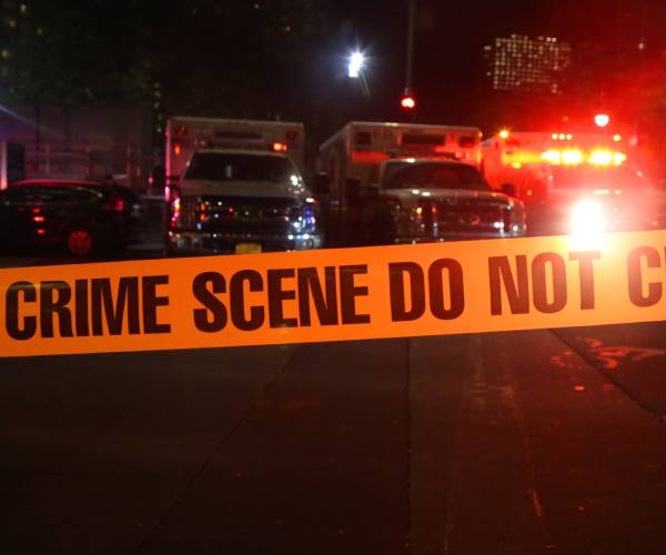crime scene tape in front of emergency vehicles