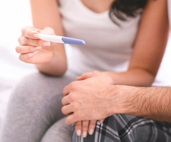 man and woman looking at a pregnancy test
