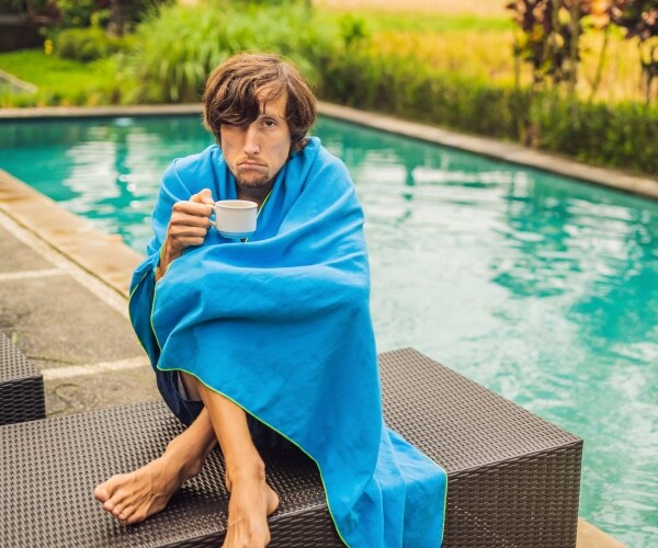 man sick, sipping tea sitting beside a pool in summer