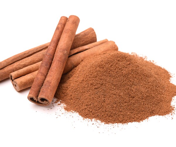 a pile of ground cinnamon and cinnamon sticks