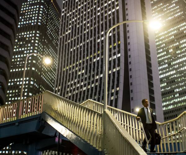 man walks down stairs at night in tokyo
