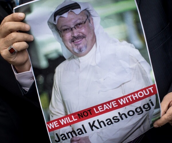 man holds poster of khashoggi in a white outfit