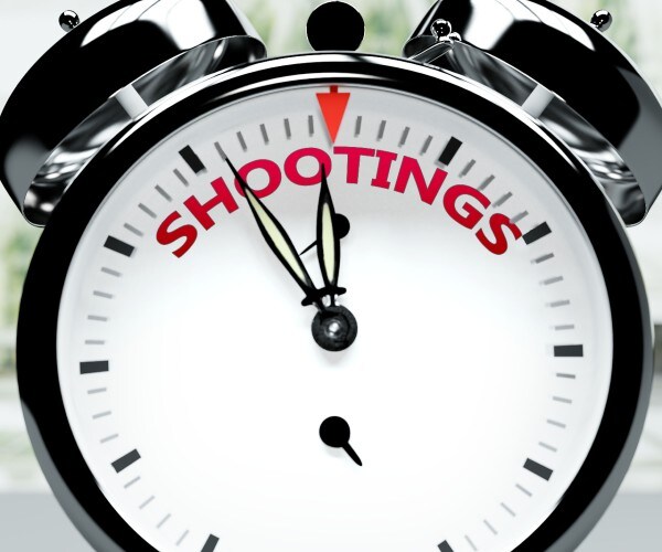 an alarm clock about to strike twelve with shootings written on it