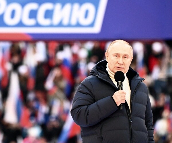 Vladimir Putin speaks into a microphone at at concert