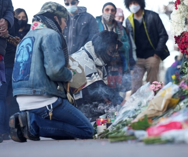 Mourners burn incense as they gather outside the door of a tattoo parlor
