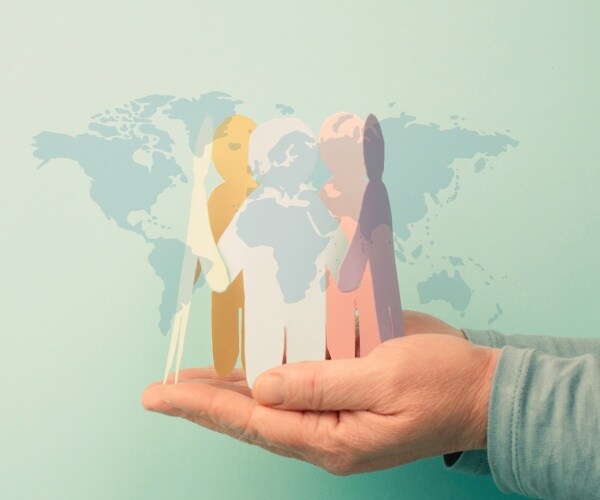 hand holding paper people with world in background