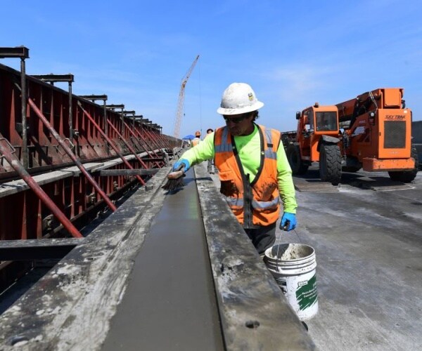 worker lays cement on high speed rail in california