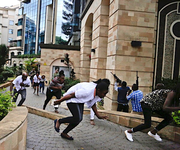 people flee as security forces aim their weapons at the buildings of a hotel complex in nairobi, kenya on tuesday
