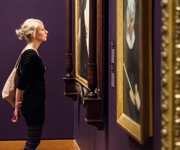 a young woman looking at paintings in a museum