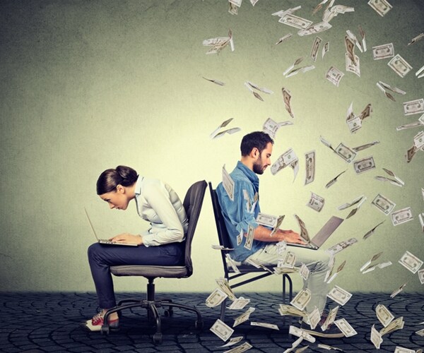 woman working on laptop sitting next to young men under money rain