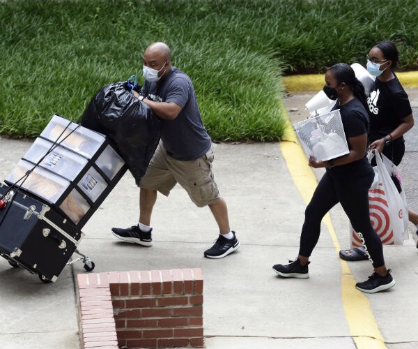 college students carry bags and belongings with assistance from a family member, all wearing masks