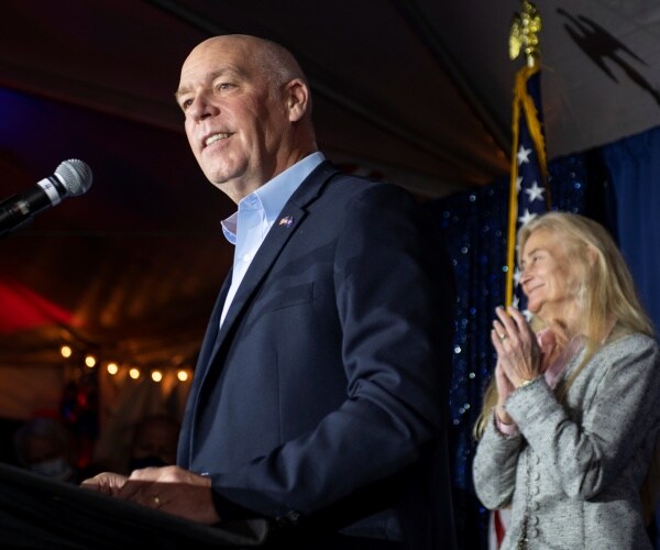 gianforte in a suit and blue shirt speaking into a mic at a podium 